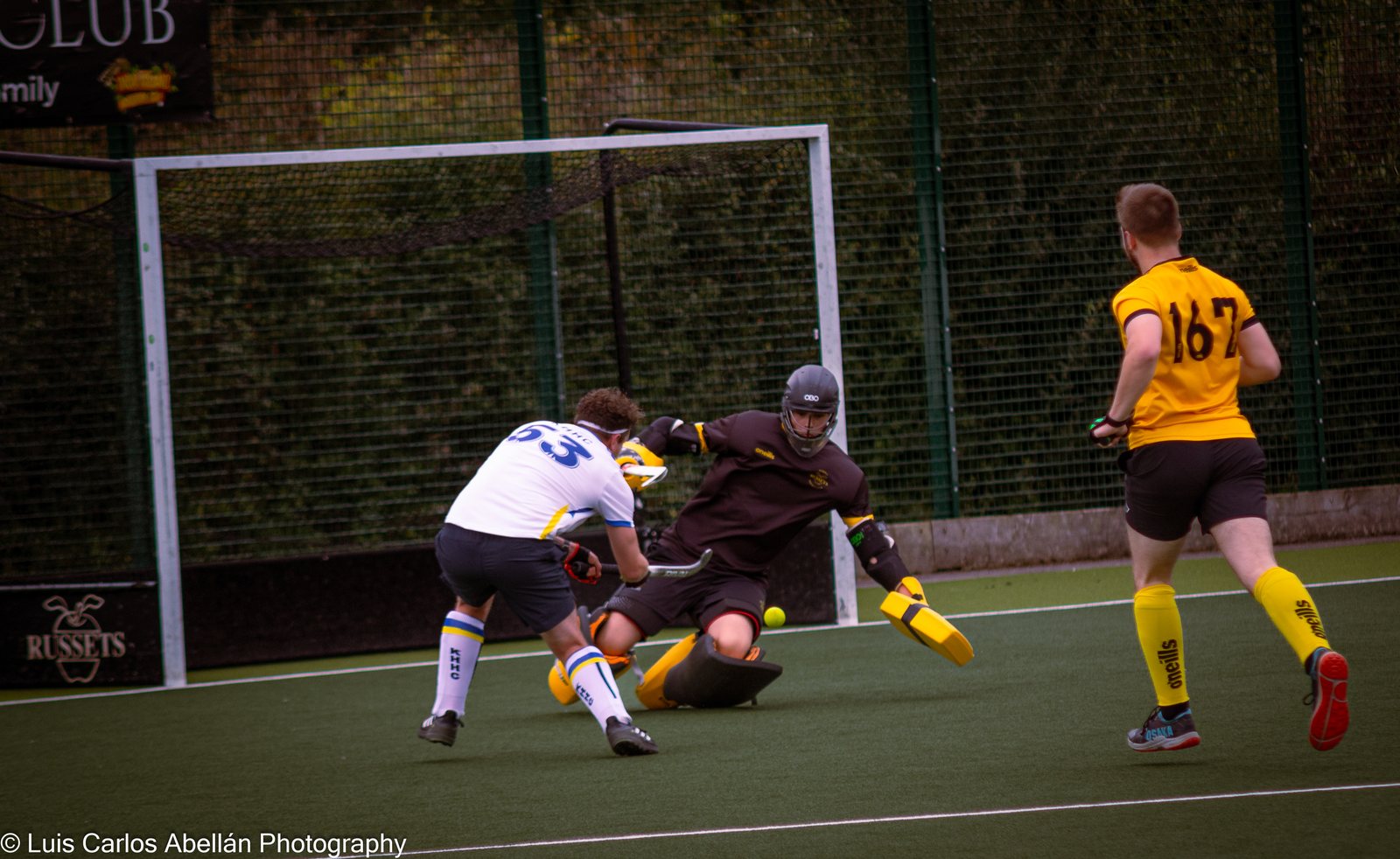 Hockey players battle for the ball close to goal.