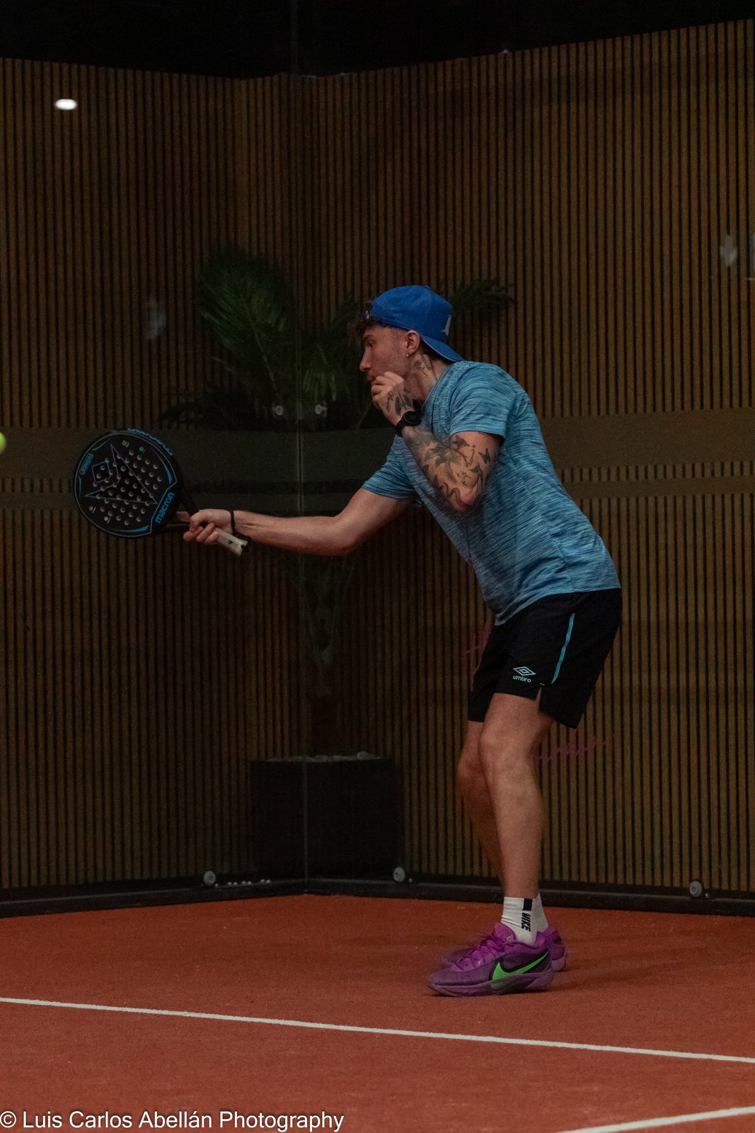 Padel player tracks the ball during an indoor rally.