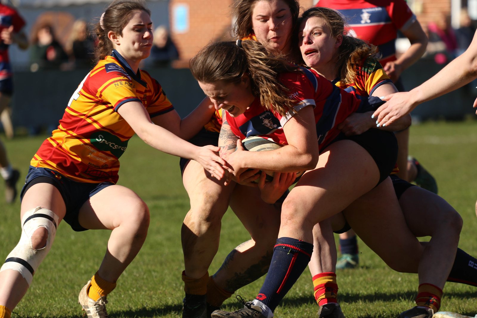 Women rugby defenders bring down a ball carrier.